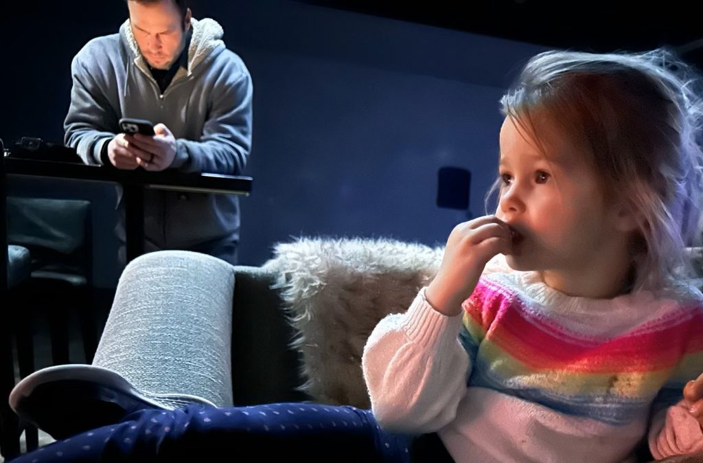 Small business owner working late at home, while daughter is ignored.